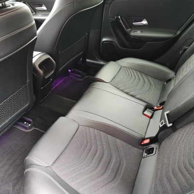 Bancos traseiros de carro em tecido cinzento e couro preto com luz ambiente púrpura