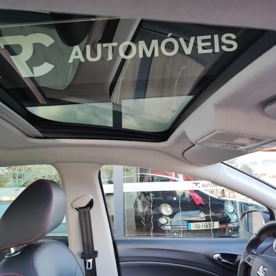Interior de carro com teto panorâmico e logomarca PC AUTOMÓVEIS no vidro