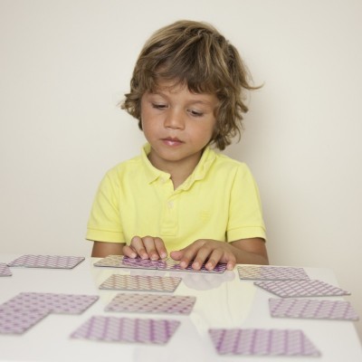 Criança a jogar cartas numa mesa branca