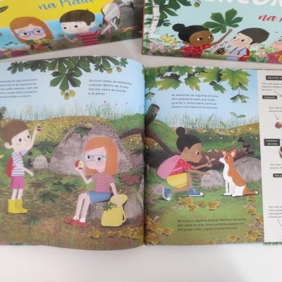 Livro infantil aberto com ilustrações de crianças na natureza e texto em português