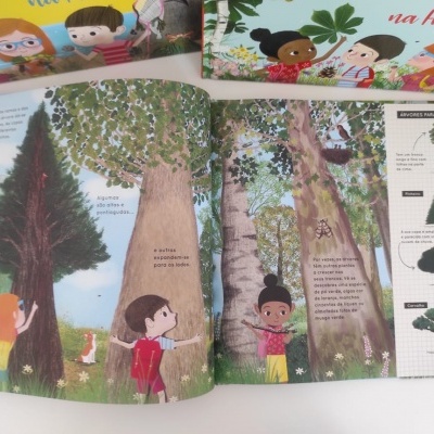 Livro infantil ilustrado aberto a mostrar páginas sobre árvores e crianças, com texto em português e embalagem ao fundo