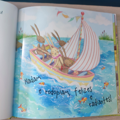 Página ilustrada de livro infantil com coelhos num barco e texto em português