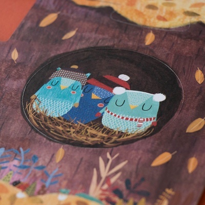 Livro infantil com ilustração de três corujas num ninho sobre fundo castanho com folhas amarelas.