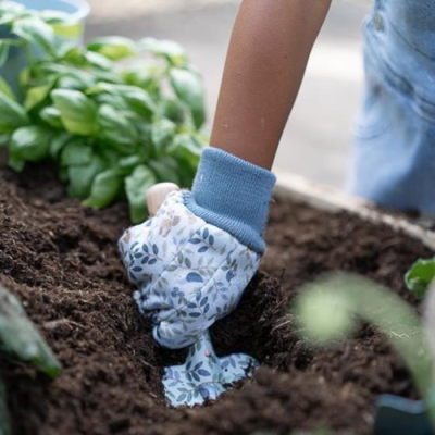 Luvas de jardinagem brancas e azuis a cavar terra num canteiro