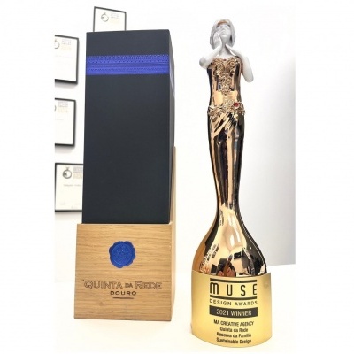 Garrafa decorativa dourada com caixa preta e base de madeira sobre fundo branco.