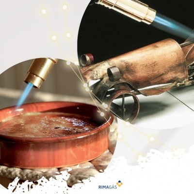 Maçarico dourado a aquecer recipiente de cerâmica castanha com líquido a borbulhar