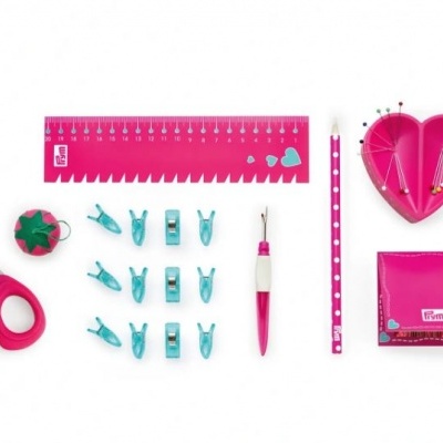 Conjunto rosa e azul de ferramentas de costura e escrita dispostas em fundo branco