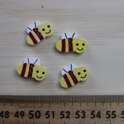 Quatro autocolantes abelha amarelos e castanhos sobre madeira com régua