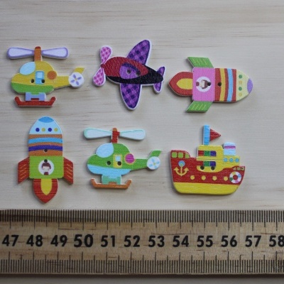 Seis botões de madeira coloridos com formas de veículos exibidos perto de uma régua sobre uma superfície de madeira clara