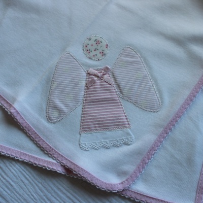 Toalha branca com borda rosa e aplicação de anjo em tecido às riscas rosa e branco