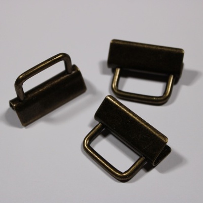 Três fivelas metálicas bronze escuro em superfície branca