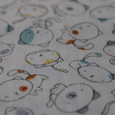 tecido branco com padrão de desenhos de gatos em azul, laranja e amarelo