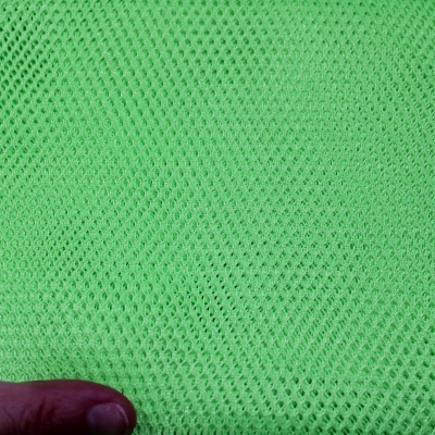 Tecido verde-limão com padrão de malha e mão esquerda segurando