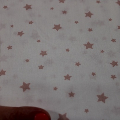 Tecido branco com estrelas cor de rosa e mão segurando o canto