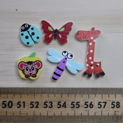 Cinco botões decorativos em formas animais e de fruta com cores vibrantes sobre madeira clara