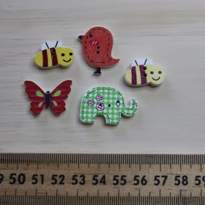 Cinco ímanes ou botões de madeira coloridos em formas diversas sobre madeira com régua