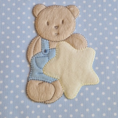 Urso de peluche castanho em tecido azul com pontos brancos