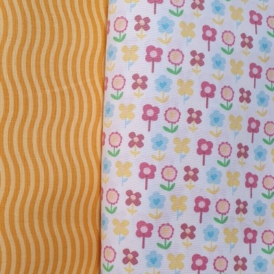 Dois tecidos em padrões distintos, um castanho com ondas largas e outro branco com flores coloridas