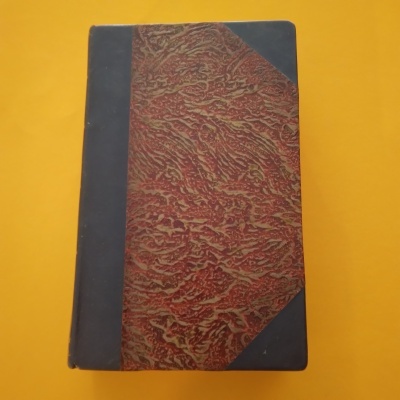 Livro capa dura com padrão marmoreado vermelho e textura preta nas bordas