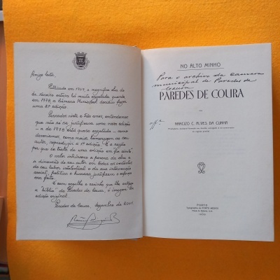 Livro aberto com texto manuscrito e impresso em português sobre fundo laranja