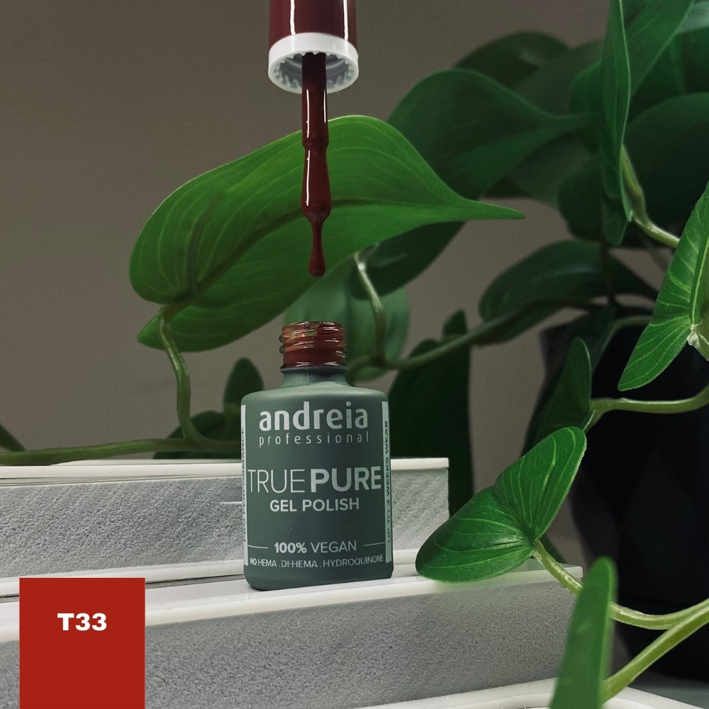 The Gel Polish Andreia True Pure T33 (Castanho) Frasco de esmalte em gel Andreia Professional True Pure cinza com pincel vinho e folhas verdes ao redor