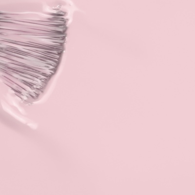 Pincel com cerdas brancas e verniz rosa claro em fundo rosa