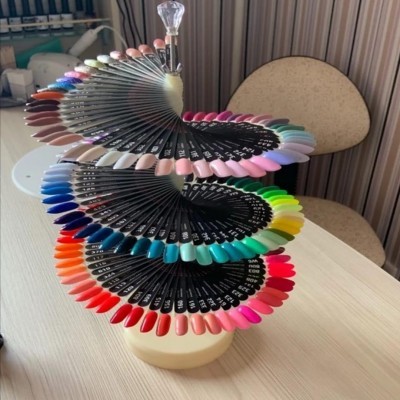 Mostruário de unhas artificiais coloridas em espiral sobre mesa de madeira clara