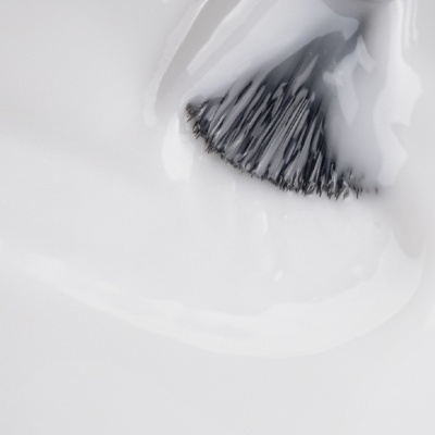 Pincel com cerdas pretas a aplicar verniz ou esmalte branco