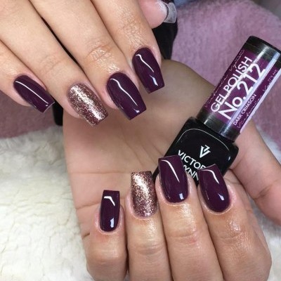 Unhas pintadas de roxo escuro e glitter com frasco de verniz gel