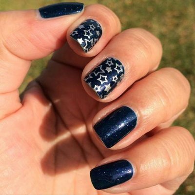 Unhas pintadas em azul escuro com estrelas brancas decorativas