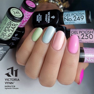 Mão com unhas pintadas de várias cores rodeada por frascos de verniz em gel Victoria Vynn