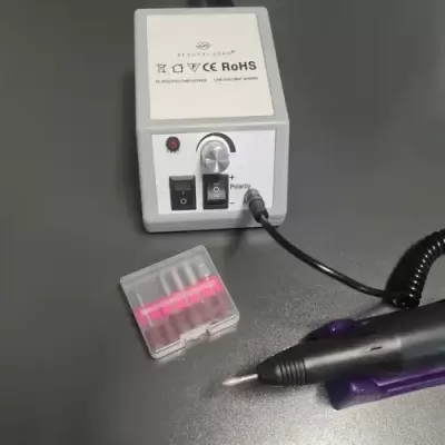 Aparelho elétrico branco com botão e seletor, com estojo transparente e caneta preta em mesa cinza