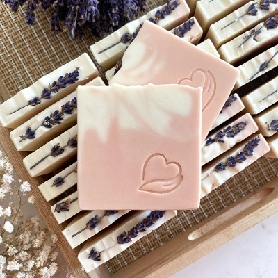 Sabonetes rosa e bege com coração gravado em bandeja de madeira com lavanda seca