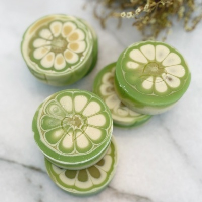 Sabonetes verdes redondos com padrão de gomos de citrino em superfície branca