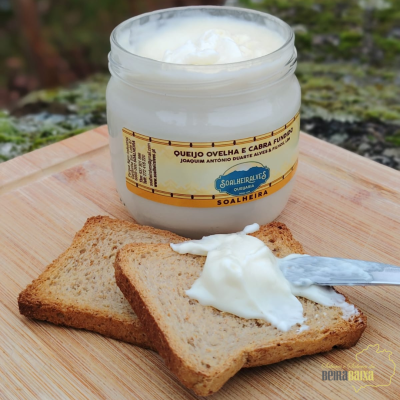 Frasco de queijo cremoso e fatias de pão integral numa tábua de madeira