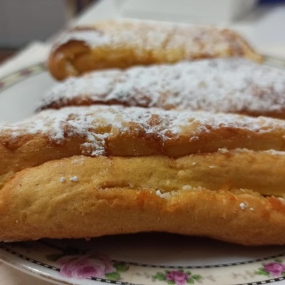 Três pastéis de massa folhada com açúcar em pó num prato branco com flores