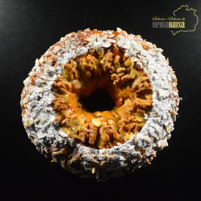 Bolo redondo com amêndoas tostadas, açúcar em pó e nozes, texto 'Sabores e Sabores da BEIRA BAXA'.
