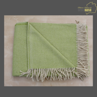 Manta verde com padrão geométrico e franjas brancas