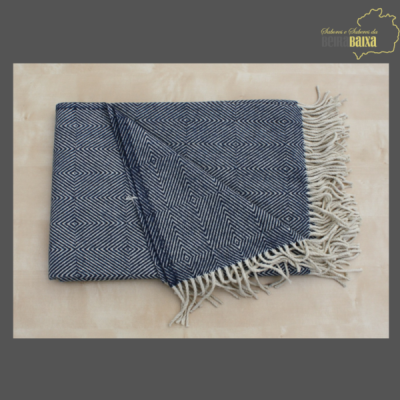 Manta azul escura com padrão geométrico branco e franjas brancas