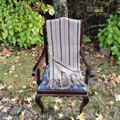 Cadeira de madeira escura com estofado azul e xale de lã às riscas num jardim.