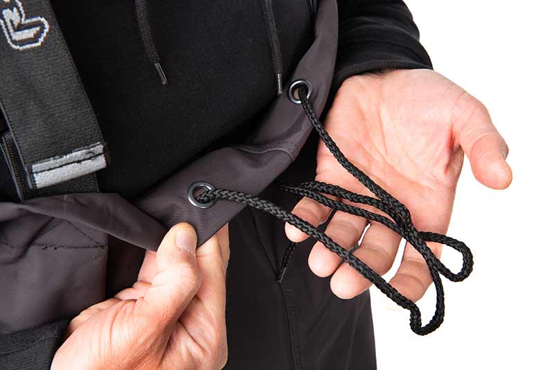 Detalhe de vestuário preto com cordão trançado e ilhós metálicos