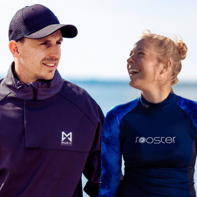 Dois adultos com roupas desportivas perto do mar com logótipos 'MAGIC' e 'rooster'