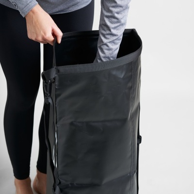 Saco desportivo preto resistente com alças ajustáveis e fecho, sendo manuseado