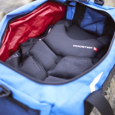 Sacola azul aberta mostrando colete de proteção preto com marca 'ROOSTER'