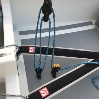 Interior de embarcação com correias pretas, cordas azuis e blocos