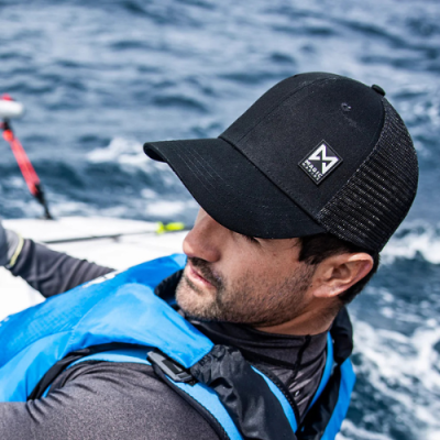 Homem de boné preto com etiqueta e colete salva-vidas azul no mar