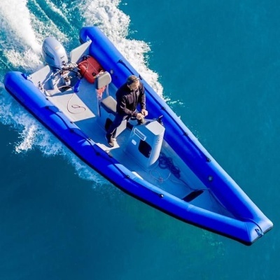 Barco insuflável azul com motor e homem a conduzir