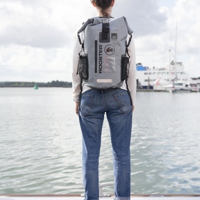 Mochila cinzenta impermeável Rooster 35L junto a cais com barcos