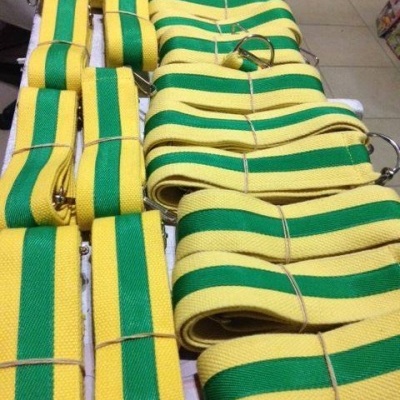 Tiras de tecido amarelo com faixas verdes e argolas metálicas