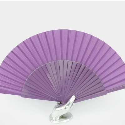 Leque lilás apoiado numa mão prateada em fundo branco